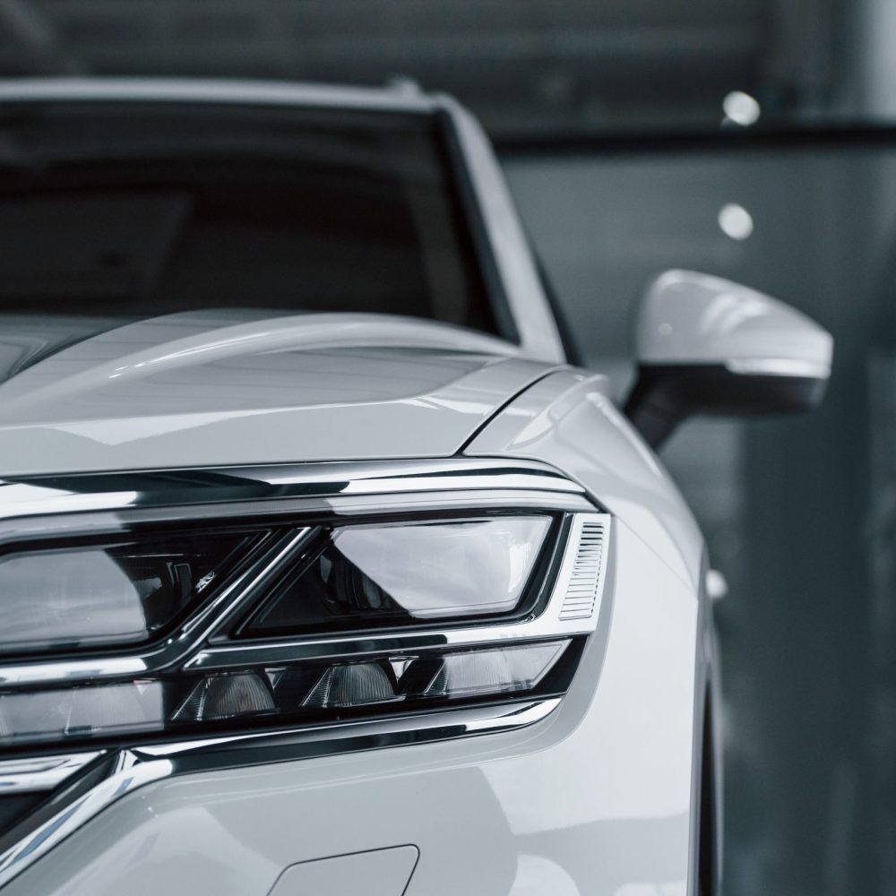 Attention to details. Particle view of modern luxury white car parked indoors at daytime.
